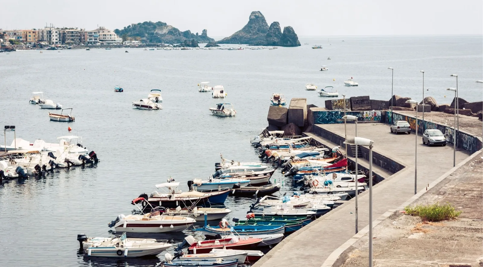 Aerial view of Aci Trezza's fishing harbour with the Faraglioni and Isola Lachea offshore