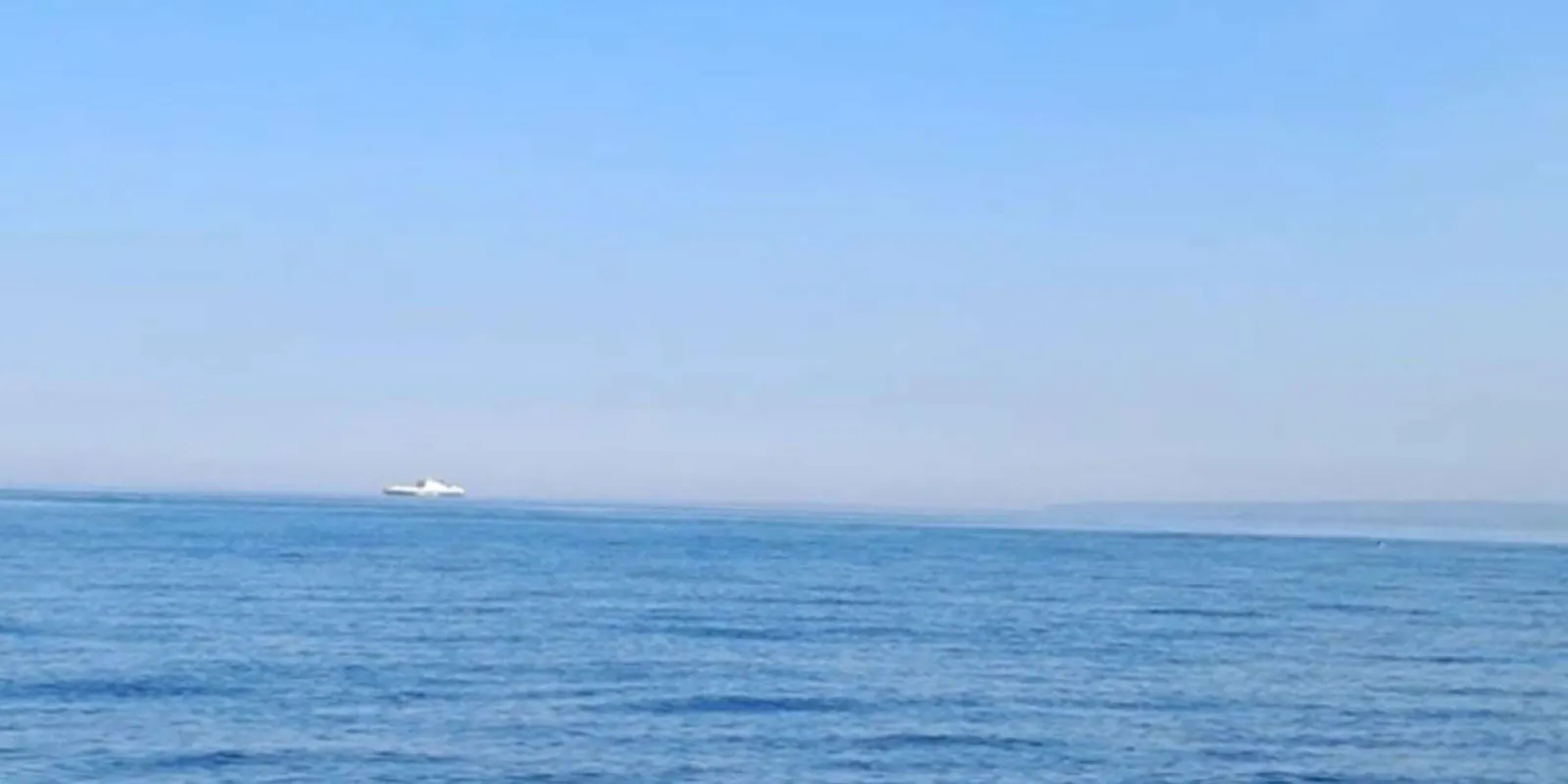Small boat crossing calm water off Aci Trezza at dusk during the sunset cruise