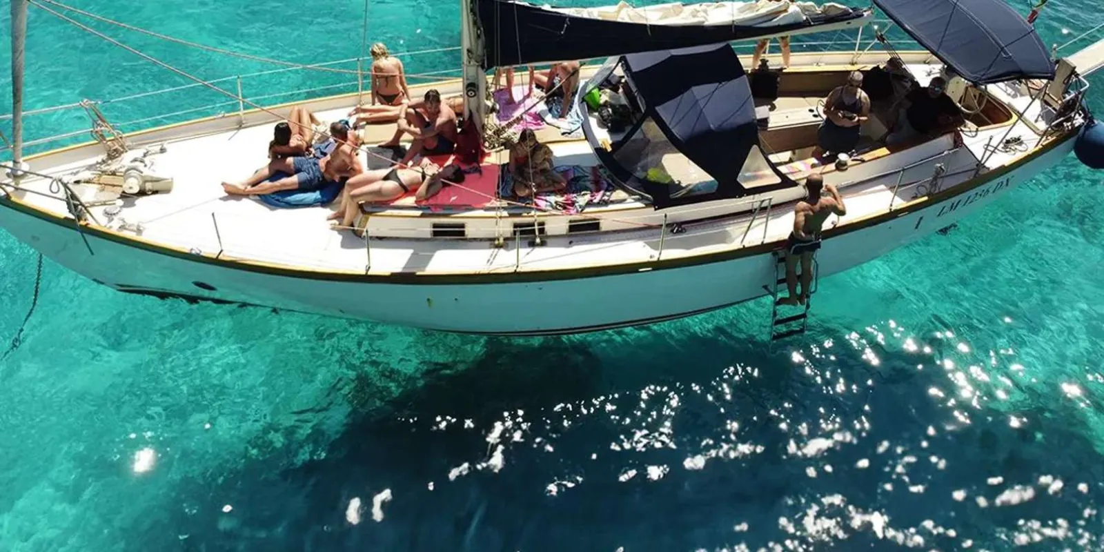 Sailing crew and guests relaxing on deck as the boat cruises the Cyclops Coast