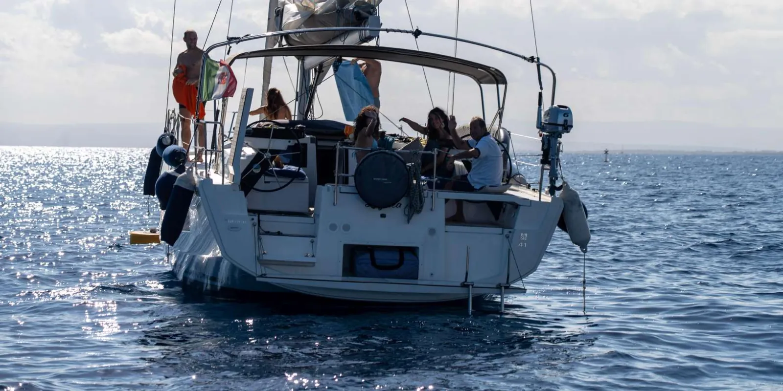 Guests relaxing on the sailboat deck with an aperitif spread and prosecco off the Cyclops Coast