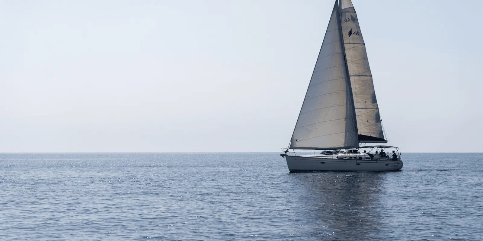 Sailboat crossing the Ionian Sea toward Aci Trezza with Mount Etna on the horizon